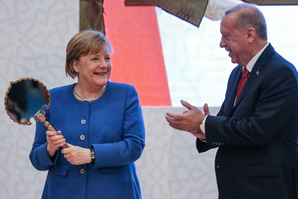 Tysklands forbundskansler, Angela Merkel, viser en gave frem, som hun har fået af den tyrkiske præsident, Recep Tayyip Erdogan, under sit besøg i Istanbul fredag.