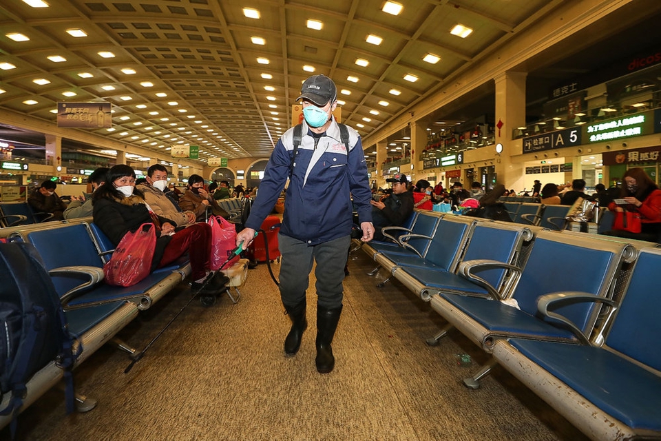 En medarbejder desinficerer togstationen i Wuhan. Byen lukker for offentlig transport torsdag formiddag. Udgående tog og fly fra byen bliver der ligeledes lukket for.