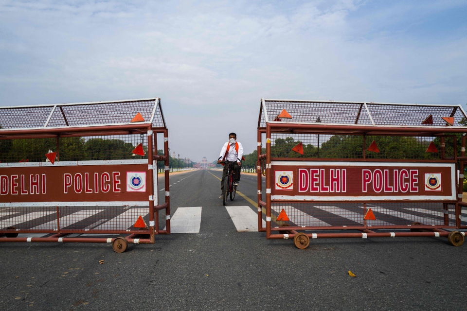 En cyklist i New Delhi kører gennem en afspærring på den mennesketomme boulevard Rajpath, der fører op til præsidentpaladset. Hele Indien lukker ned ved midnat på grund af coronavirus.